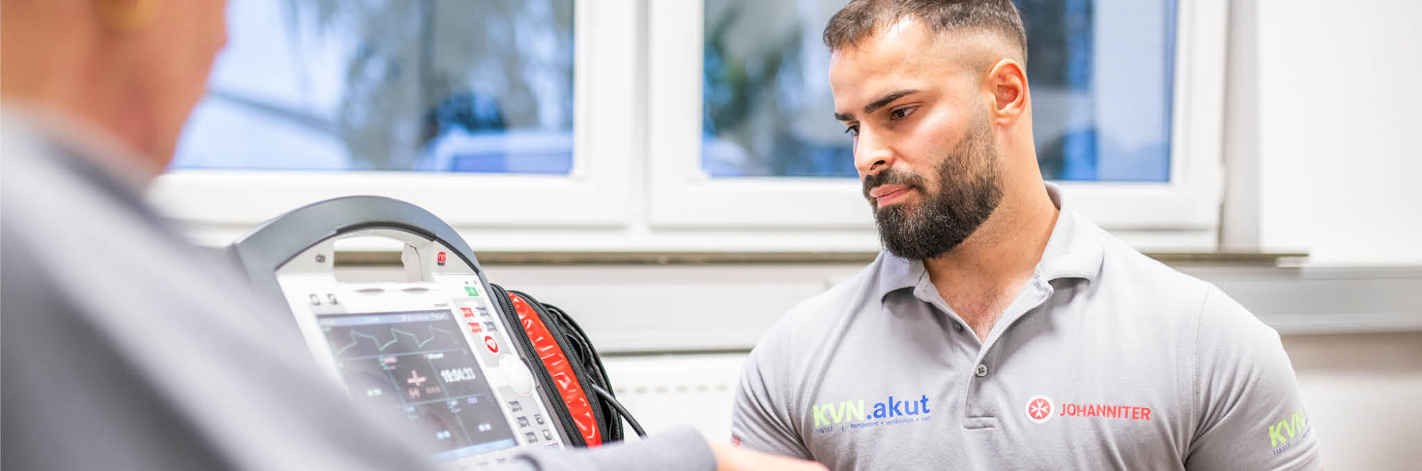 Eine Gesundheitsfachkraft im ärztlichen Bereitschaftsdienst schaut zusammen mit einer Person auf ein Messgerät.