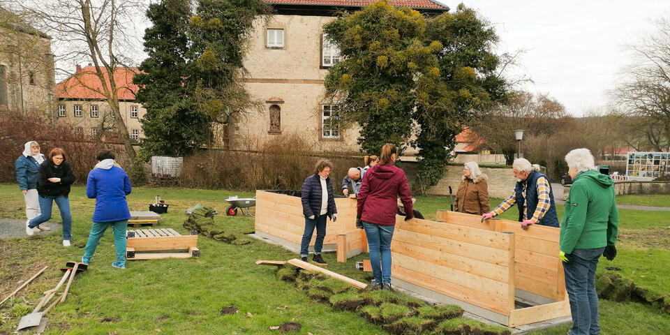 Menschen bauen Hochbeete in einem Park zusammen