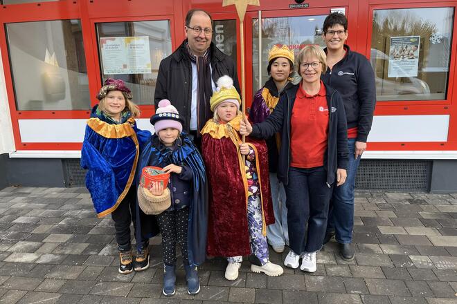 Gruppenfoto der Sternsinger mit Pfarrer Szafera und dem Leitungsteam der Tagespflege vor dem Eingang