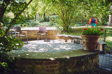 Schattiger Platz mit zwei Stühlen in einer gemauerten runden Einfassung im Garten Johanniterhaus Sinzig