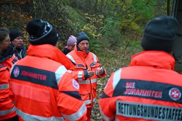 Ein Staffelführer der Rettungshundestaffel bespricht den Einsatz mit seiner Staffel im Wald.