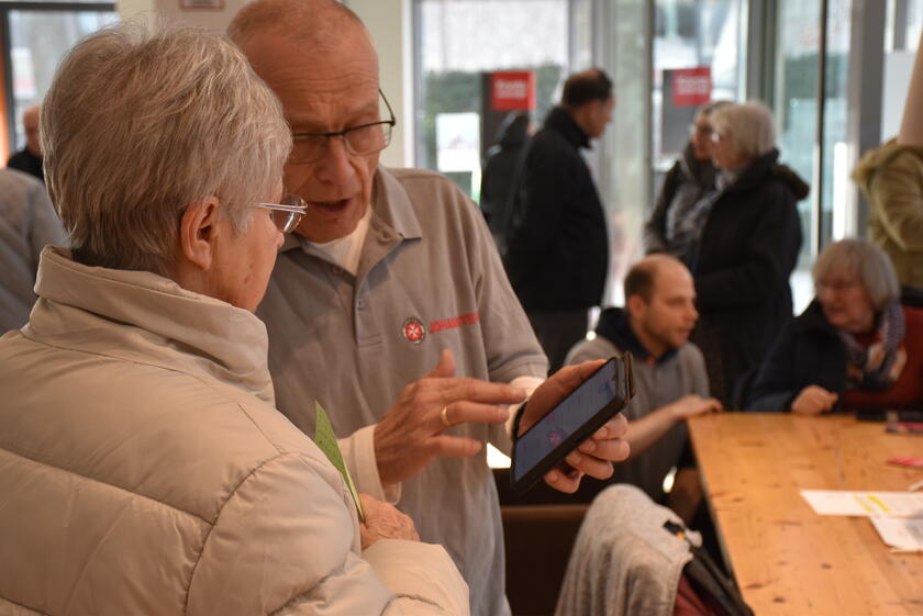 ein Mitarbeiter der Johanniter erklärt einer Seniorin die Funktionen ihres Smartphones