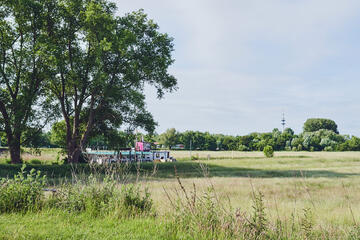 Ein weiter Blick aus der Einrichtung Johanniter Seniorenanlage Heinrich-Gau auf Felder und ein Schiff auf dem Fluss