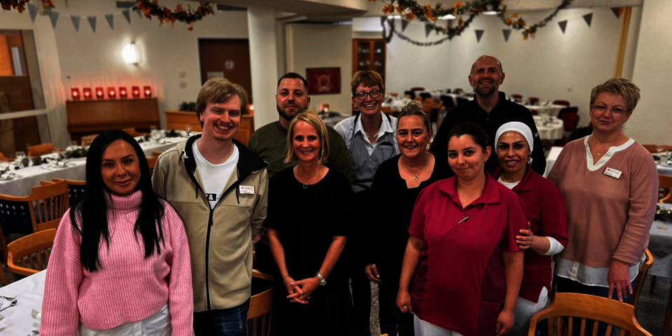 Eine Gruppe aus zehn lächelnden Manner und Frauen steht im Restaurant des Stifts