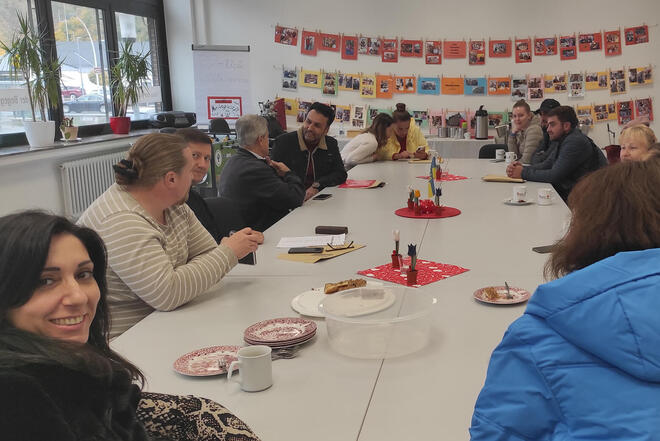 Menschen sitzen um einen großen Tisch und tauschen sich aus