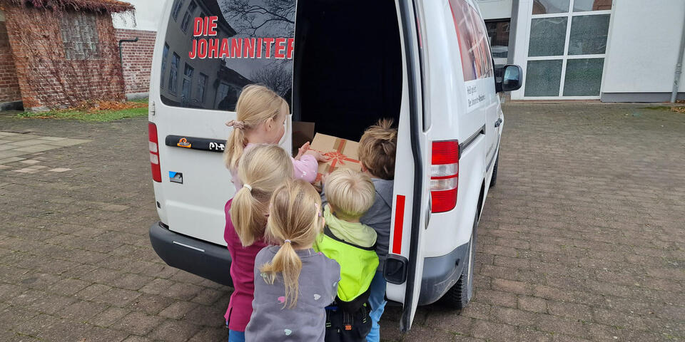 Kinder packen Weihnachtstrucker-Pakete in ein Auto