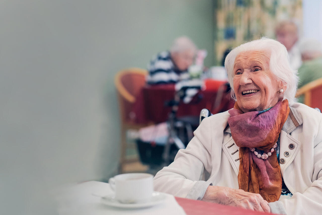 Bewohnerin trinkt Kaffee und lacht