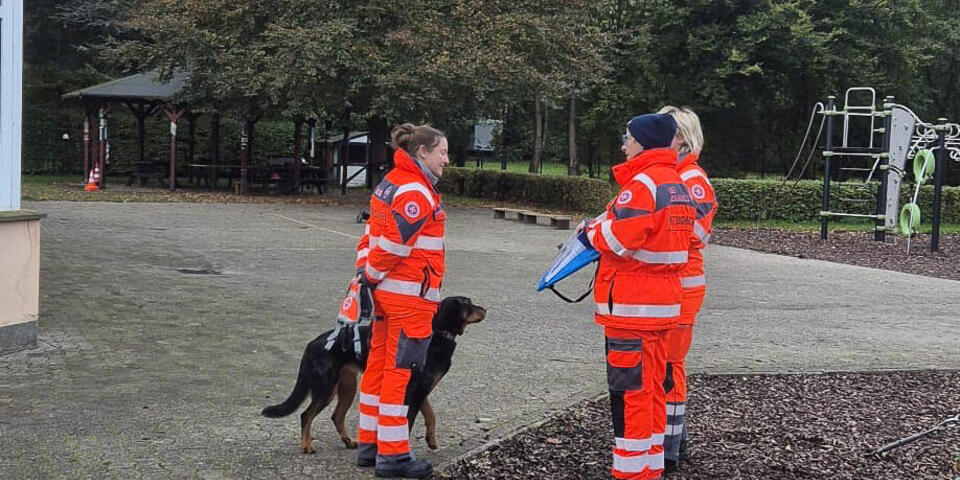Eine Johanniterin mit Hund im Gespräch mit Prüferinnen