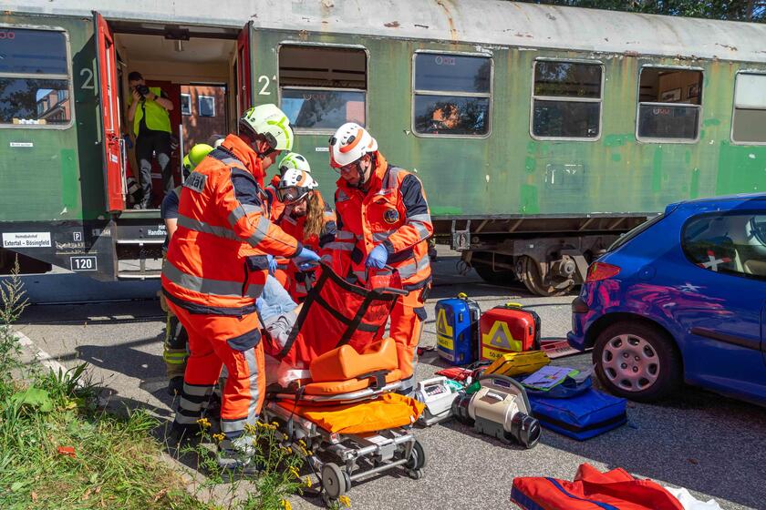 Einsatzkräfte der Schnell-Einsatz-Gruppe Sanität legen eine verletzte Person auf eine Trage.