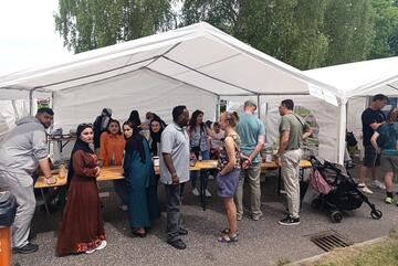 Um einen Informationsstand herum stehen Menschen