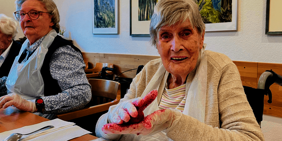 zwei Frauen sitzen am Tisch und tragen Farbe auf Eier auf