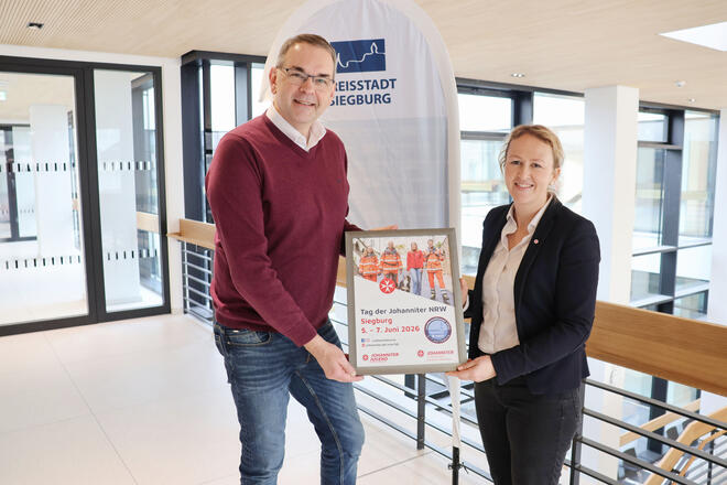 Das Bild zeigt Bürgermeister Stefan Rosemann mit Regionalvorständin Verena Dienst bei der Plakatübergabe.