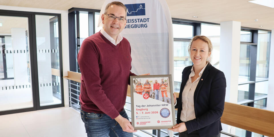 Das Bild zeigt Bürgermeister Stefan Rosemann mit Regionalvorständin Verena Dienst bei der Plakatübergabe.