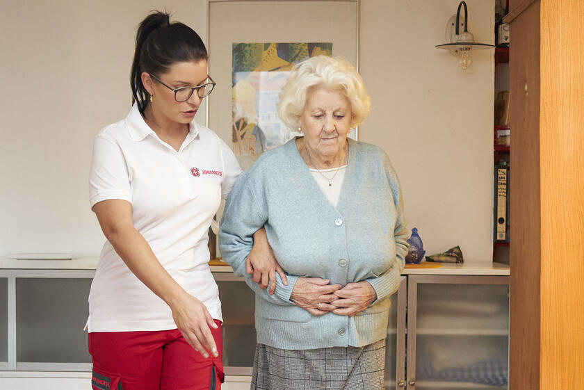 Johanniter Fachkraft weißt Seniorin auf Bodenunebenheiten in der Wohnung hin.