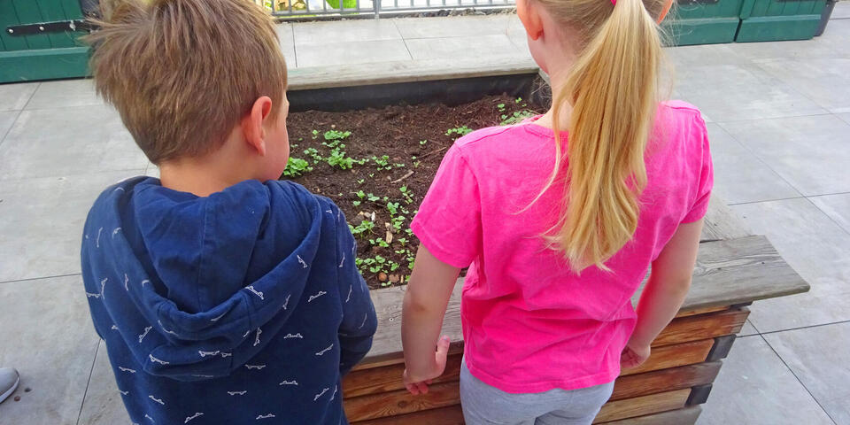 Zwei Kinder vor einem Hochbeet