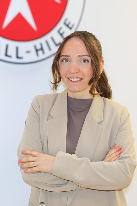Eine brünette junge Frau mit Zopf vor einem Johanniter-Logo