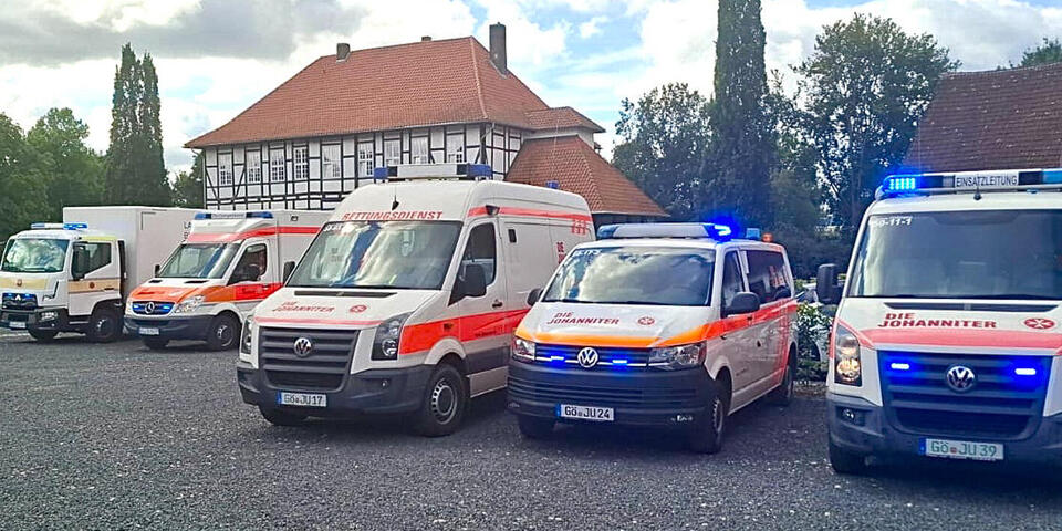 Johanniter-Einsatzfahrzeuge vor einem alten Anwesen