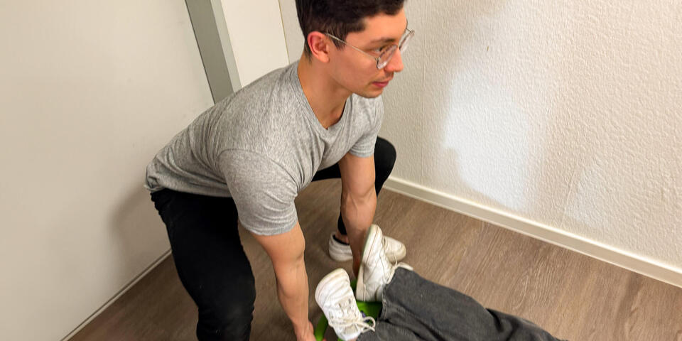 Ein junger Mann zeigt das richtige Anheben einer Trage