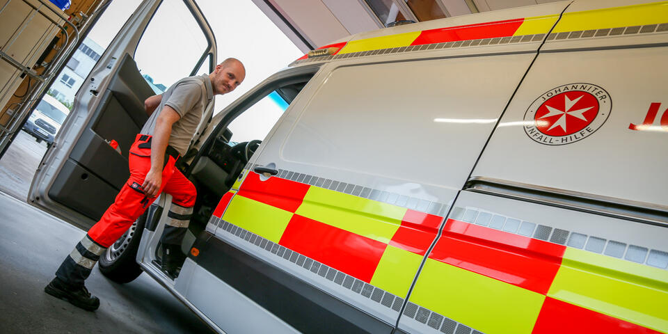 Einsatzkraft steigt in geöffneten Rettungswagen in der Fahrzeughalle