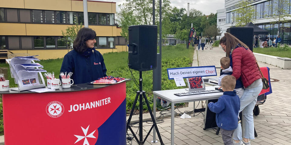 Eine Frau steht mit zwei Kindern an einem Rollpiano