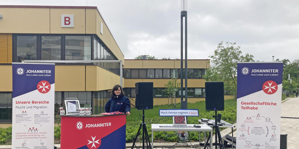 Eine junge Frau steht an einem Johanniter-Infostand