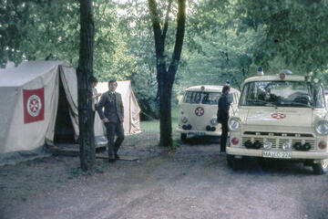 Sanitäter und Fahrzeuge vor einem Sanitätszelt im Jahr 1964.