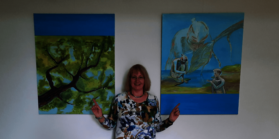 Ein Frau steht zwischen zwei Gemälden mit kräftigen Farben