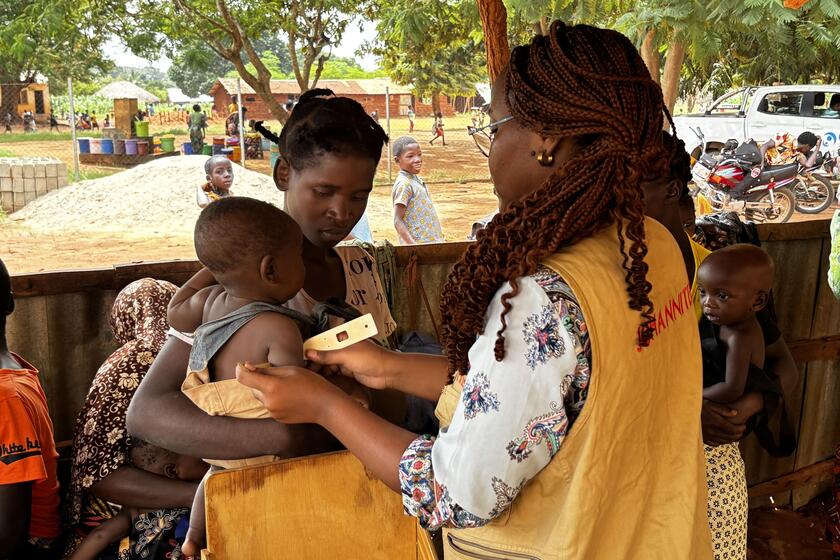 Frau mit Kleinkind auf dem Arm, das behandelt wird.