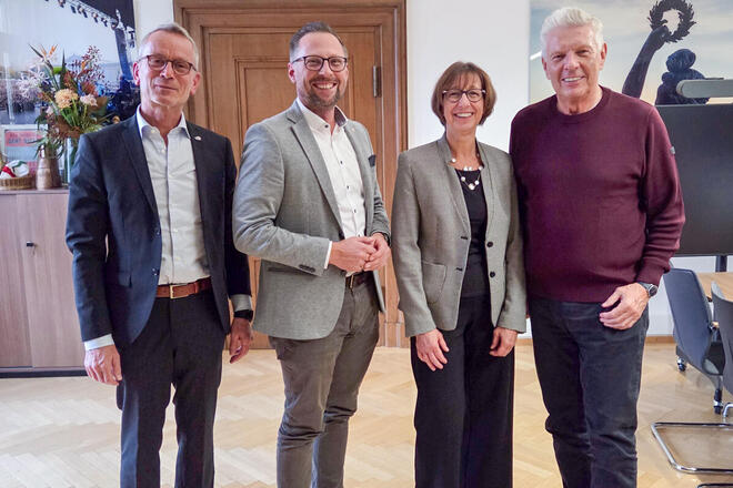 Oberbürgermeister Dieter Reiter steht in seinem Büro lächelnd neben den Boris Cramer, Susanne Lickert-Heinrich und Alfred Gahse von den Johannitern.