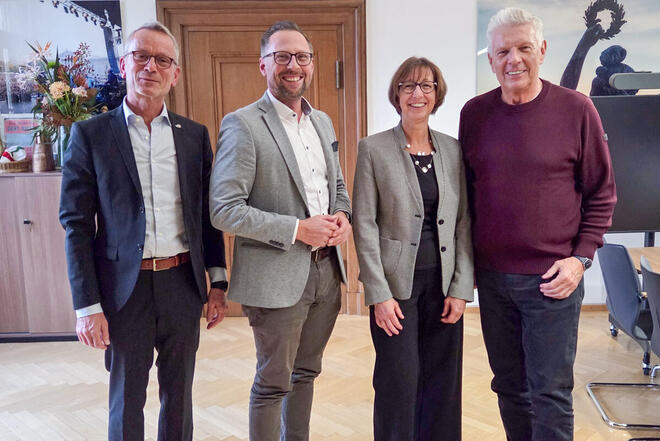 Oberbürgermeister Dieter Reiter steht in seinem Büro lächelnd neben den Boris Cramer, Susanne Lickert-Heinrich und Alfred Gahse von den Johannitern.