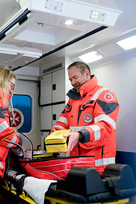 Ehrenamtliche Rettungskräfte der Johanniter arbeiten gemeinsam im Inneren eines Rettungswagens. Sie überprüfen die medizinischen Geräte und Taschen, um für einen Notfall gerüstet zu sein.