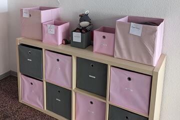 Ein Regal mit verschiedenen Fächern, darin ist Kinderkleidung..