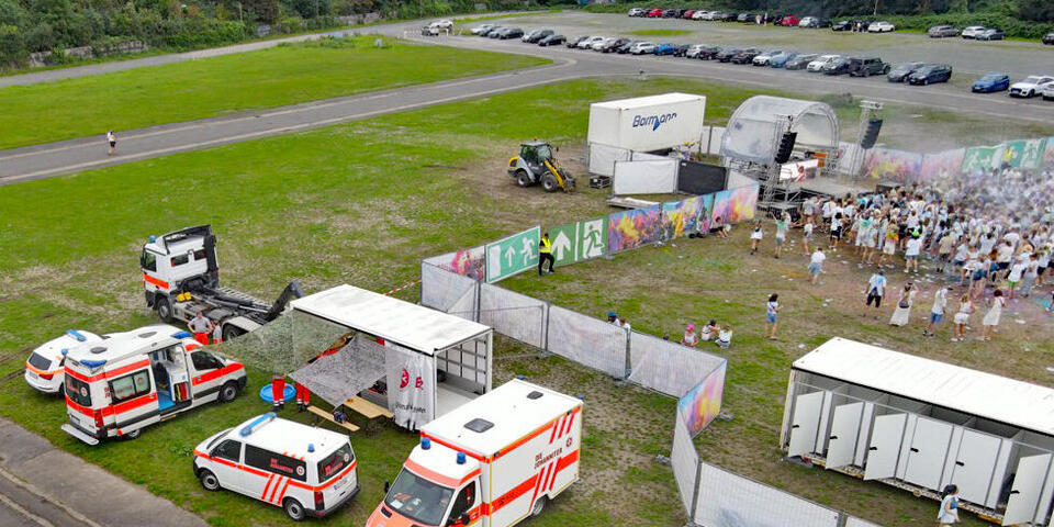 Ein Festivalgelände mit Menschen von oben mit Einsatzwagen der Johanniter