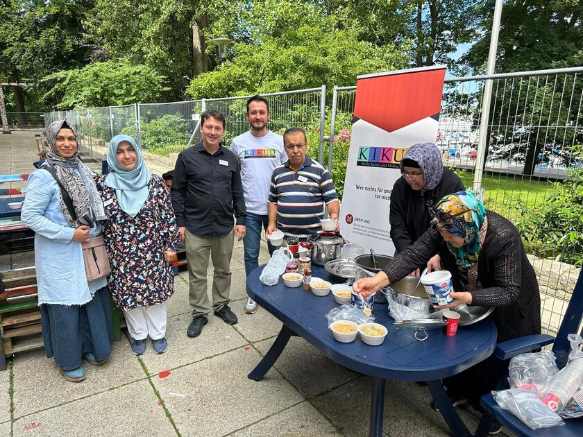 Mehrere Personen sitzen oder stehen um einen Tisch mit Speisen zum Fest