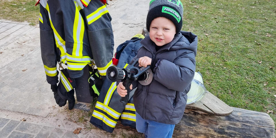 Ein kleiner Junge mit einem Feuerwehrschlauch