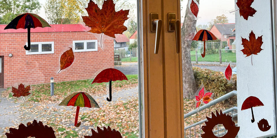 Ein Fenster mit Deko aus Blättern und ausgestanzten Igeln