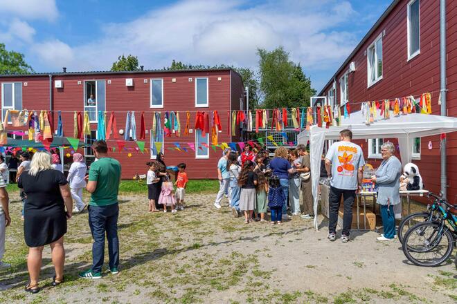Sommerfest in der Gemeinschaftsunterkunft Ostseestraße Viele Menschen stehen auf dem Außengelände der Gemeinschaftsunterkunft und vor einem Stand mit einer Tombola.