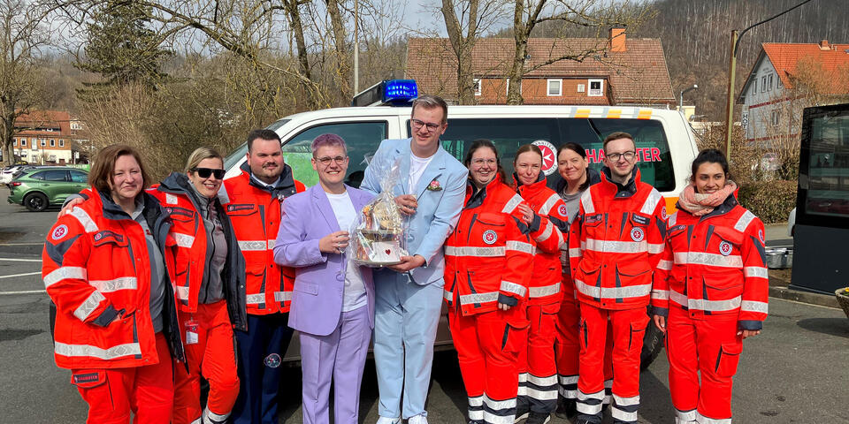 Johanniter und ein Hochzeitspaar vor einem Einsatzfahrzeug