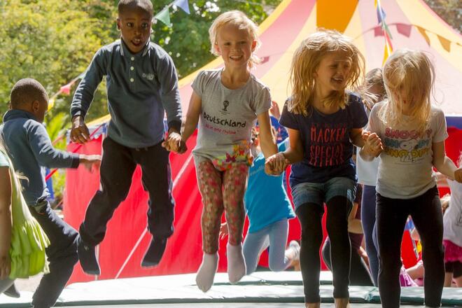 inder beim fröhlichen Springen vor einem Zelt beim Lilalu-Ferienprogramm.
