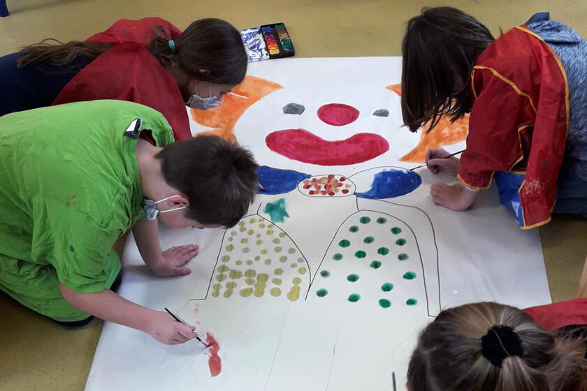 Kinder der Mittagsbetreuung malen in der Faschingszeit gemeinsam einen großen Clown.