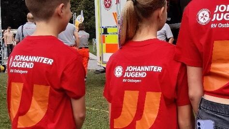 Jugendliche blicken auf einen Johanniter-Krankenwagen