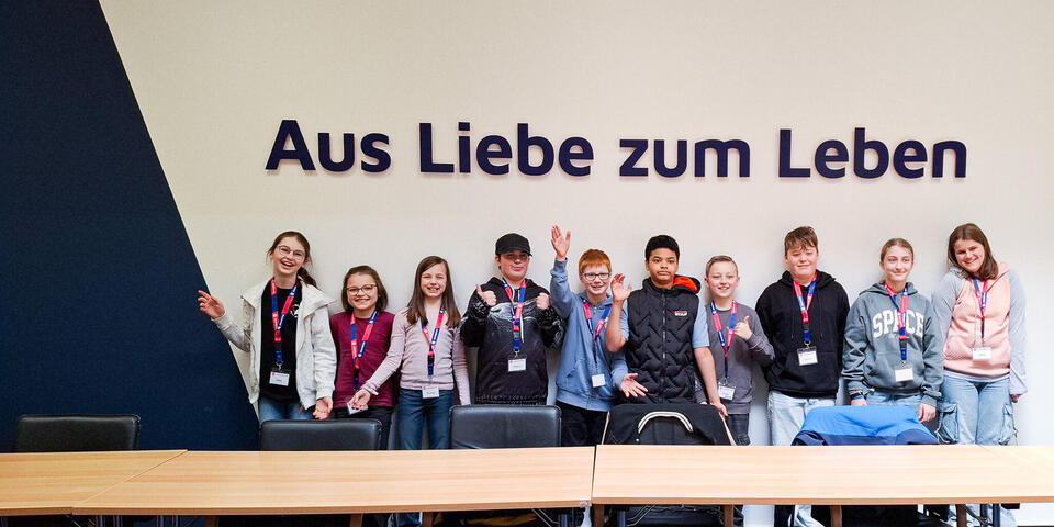 Zehn Kinder vor einer Wand. Dort steht "Aus Liebe zum Leben"