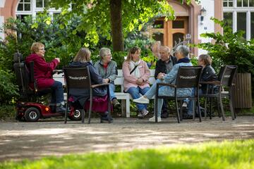 Personen auf der Plauderbank im Grünen