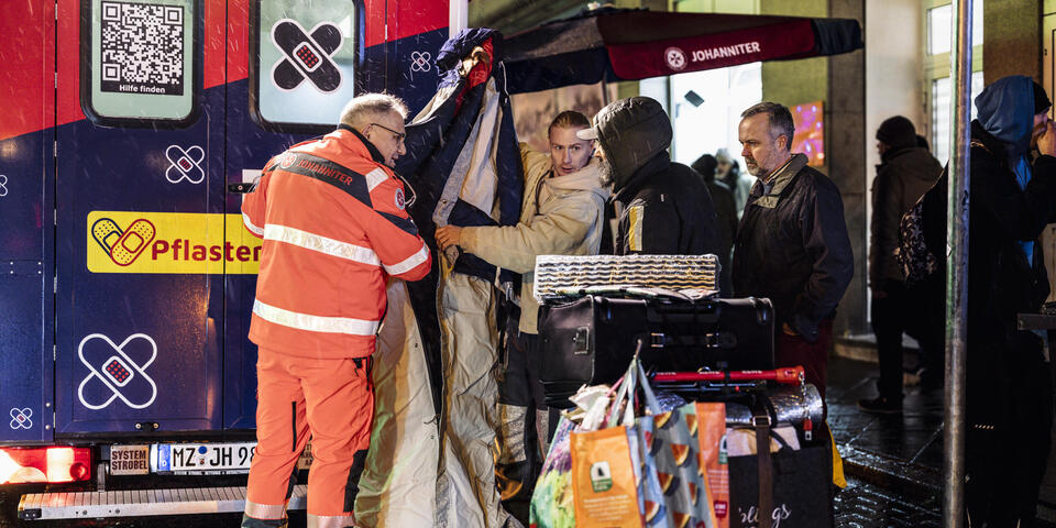 Beim Pflasterlaster wird einem Obdachlosen eine Funktionsjacke erklärt. 