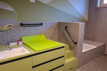 Wickelplatz im Krippenbad: grüner Wickeltisch neben Waschbecken und Dusche.