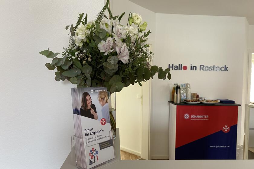 der Tresen am Empfang der Logopädiepraxis ist mit einem Strauß Blumen geschmückt