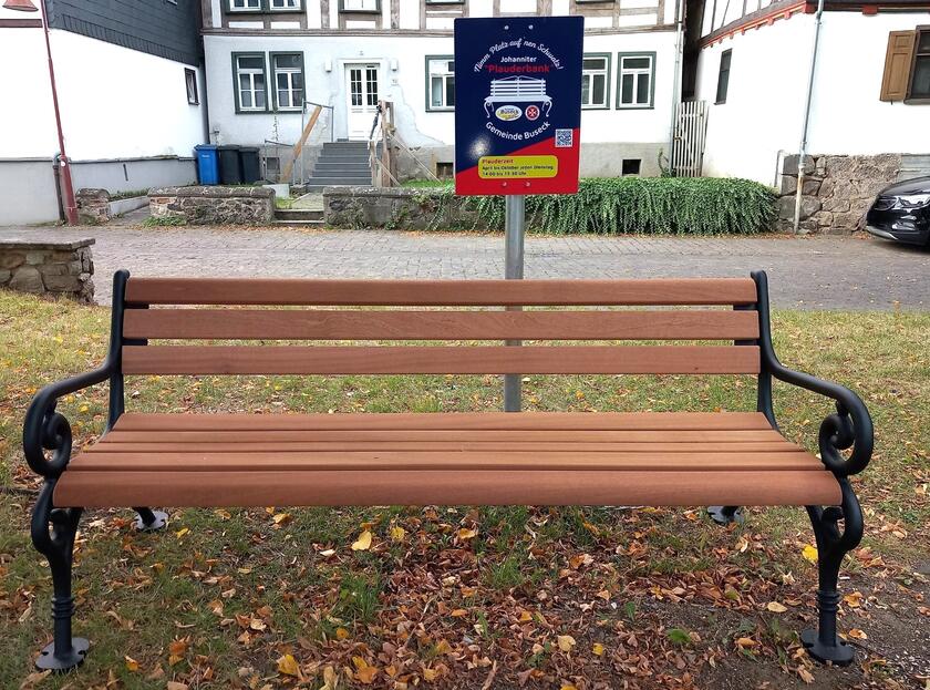 Holzbank mit Plauderbankschild im Hintergrund
