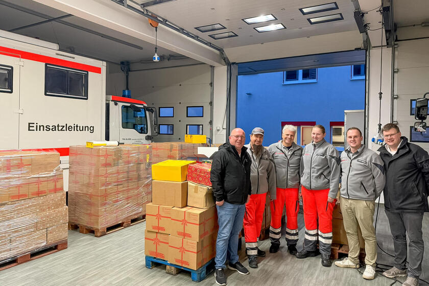 In der Fahrzeughalle stehen Paletten mit Paketen und sechs Helfer der Johanniter.