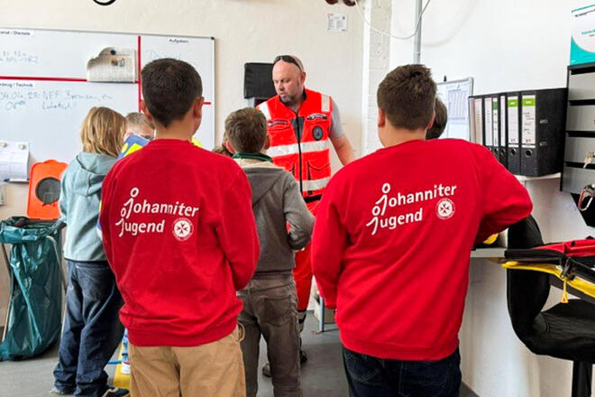 Kinder lauschen einem Rettungdienstmitarbeiter