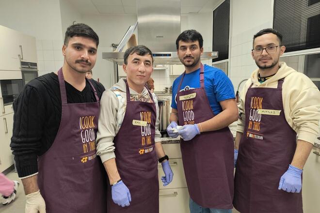 Vier Bewohnende der LUK mit Kochschürzen in der Küche